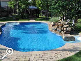 In-ground pool with a waterfall achievements by Piscines René Pitre